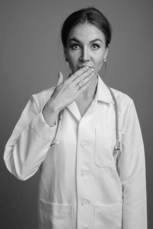 Young beautiful woman doctor against gray backgroundの写真素材