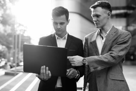Two businessmen working together outside with laptop computerの写真素材