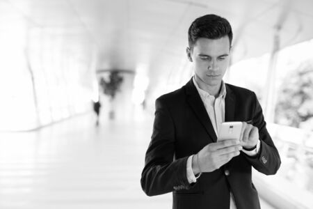 Young handsome businessman using mobile phone outdoorsの写真素材