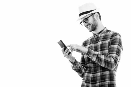Profile view of happy young man smiling while using mobile phone