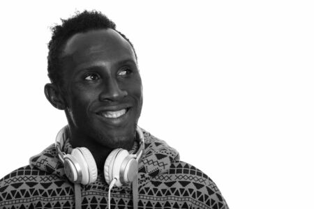 Thoughtful young happy African man smiling and wearing headphones around neckの写真素材