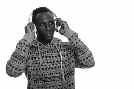 Young black African man holding headphones and listening to music while thinking
