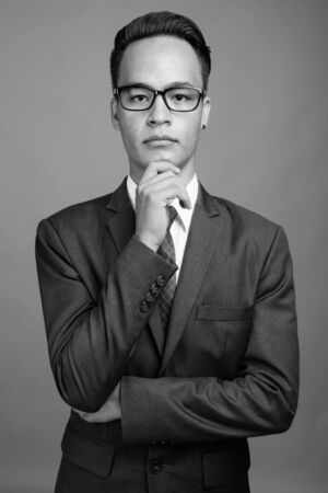 Young handsome Indian businessman against gray backgroundの写真素材