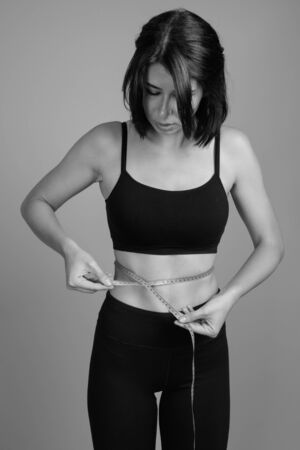 Young beautiful woman ready for gym against gray backgroundの写真素材