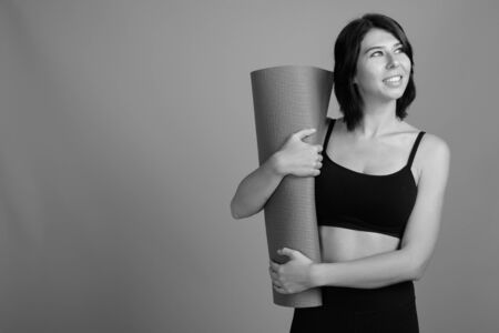 Young beautiful woman ready for gym against gray backgroundの写真素材