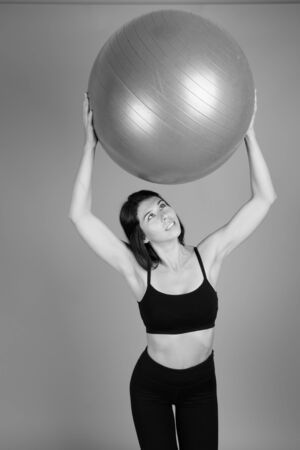 Young beautiful woman ready for gym against gray backgroundの写真素材