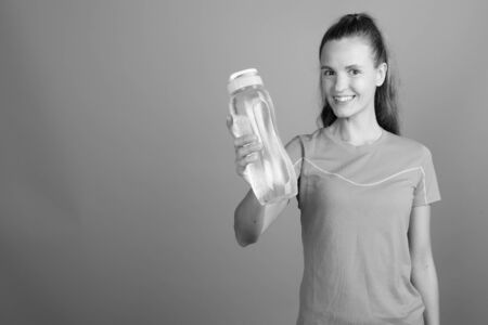 Young beautiful woman with long blond hair ready for gym against gray backgroundの写真素材