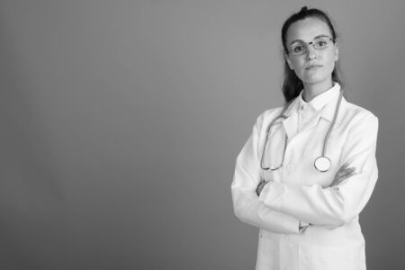 Young beautiful woman doctor against gray backgroundの写真素材