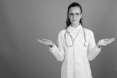 Young beautiful woman doctor against gray backgroundの写真素材