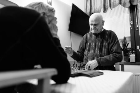 Two senior men playing chess while relaxing at nursing home in Turku, Finlandの写真素材