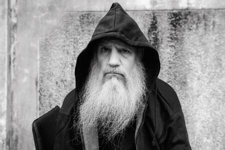 Mature bald man with long gray beard wearing hoodie outdoorsの写真素材