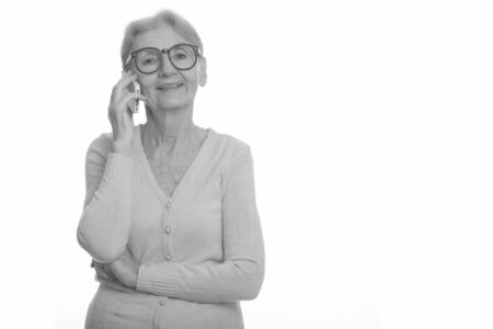 Happy senior nerd woman smiling while talking on mobile phoneの写真素材