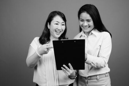 Two mature Asian businesswomen together looking documentsの写真素材
