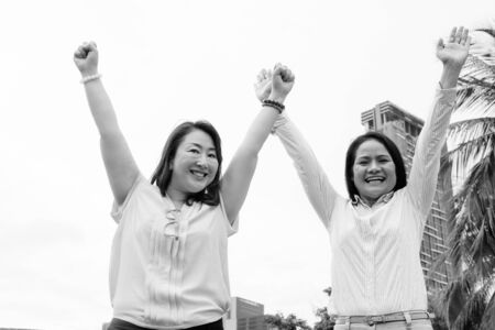 Two mature Asian women with arms raised at parkの写真素材