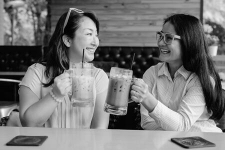 Two mature Asian women together hanging out at the coffee shop while having funの写真素材