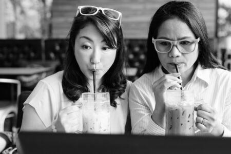 Two mature Asian women together using laptop computerの写真素材