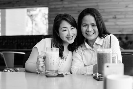 Two mature Asian women together hanging out at the coffee shop while having fun