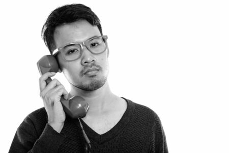 Close up of young Asian man talking on old telephone