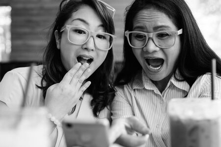 Two mature Asian women together hanging out at the coffee shop while having fun