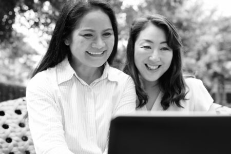 Two happy Asian women together using laptop computerの写真素材