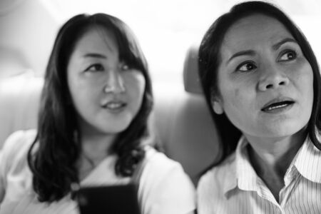 Asian women sitting inside the car while using phoneの写真素材
