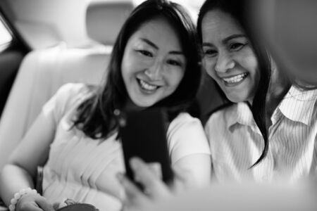 Asian women sitting inside the car while using phone