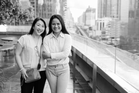 Two mature Asian women together against view of the cityの写真素材