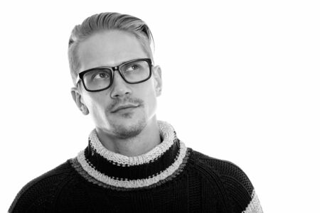 Young handsome man thinking and looking up while wearing eyeglasses