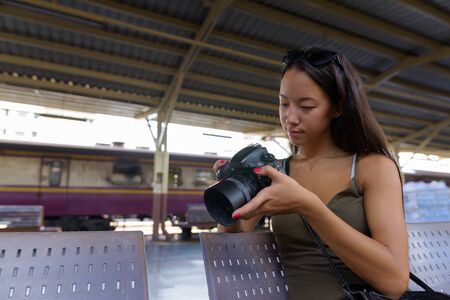Young tourist woman sitting and using DSLR camera
