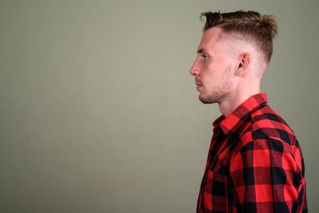 Young man wearing red checkered shirt against colored backgroundの写真素材