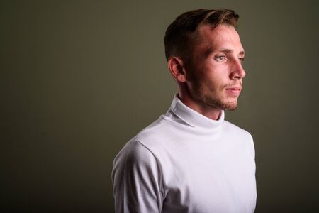 Young man wearing white turtleneck sweater against colored backgの写真素材