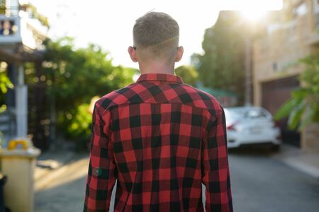 Young man wearing red checkered shirt in the streets outdoorsの写真素材
