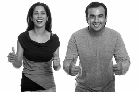 Studio shot of happy Persian couple smiling and giving thumbs upの写真素材