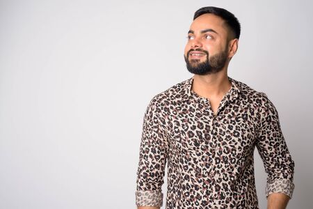 Portrait of happy young bearded Indian man thinkingの写真素材