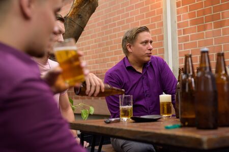 Group of men outdoors sitting and drinking beer
