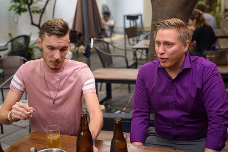 Man smoking cigarette while drinking beer with friends