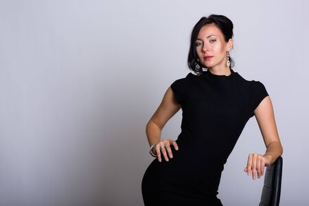 Studio shot of young beautiful businesswoman sitting on chairの写真素材