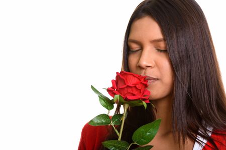 Studio shot of young beautiful Brazilian woman smelling red roseの写真素材