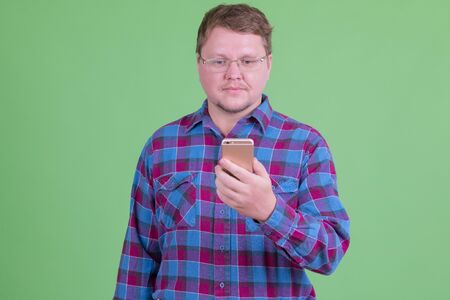 Overweight bearded hipster man with eyeglasses using phone