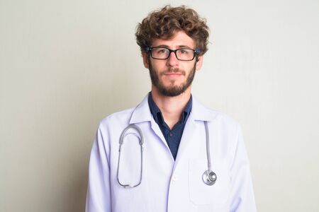 Face of young bearded man doctor with curly hair wearing eyeglassesの写真素材