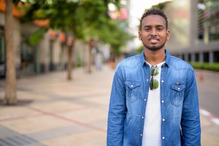 Happy young African bearded man with Afro hair in the city streetsの写真素材