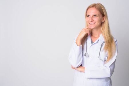 Portrait of happy young blonde woman doctor thinkingの写真素材