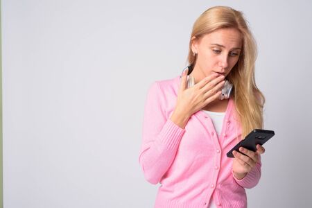 Young beautiful blonde woman using phone and looking shockedの写真素材