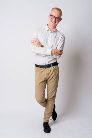 Full body shot of happy young blonde businessman smiling with arms crossedの写真素材