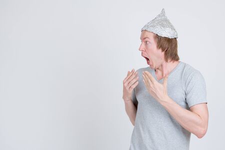 Profile view of young man with tinfoil hat looking shockedの写真素材