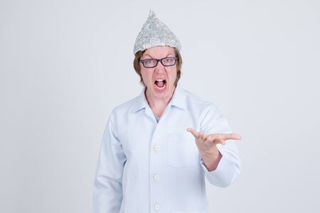 Stressed young man doctor with tinfoil hat looking angryの写真素材