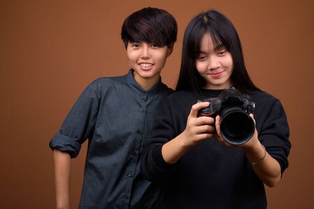 Young Asian lesbian couple together and in love against brown baの写真素材