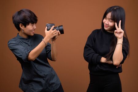 Young Asian lesbian couple together and in love against brown ba