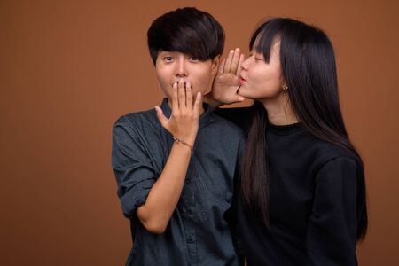 Young Asian lesbian couple together and in love against brown ba