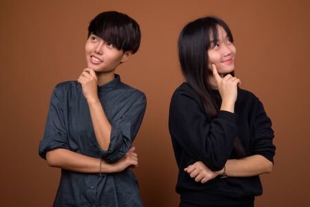 Young Asian lesbian couple together and in love against brown baの写真素材